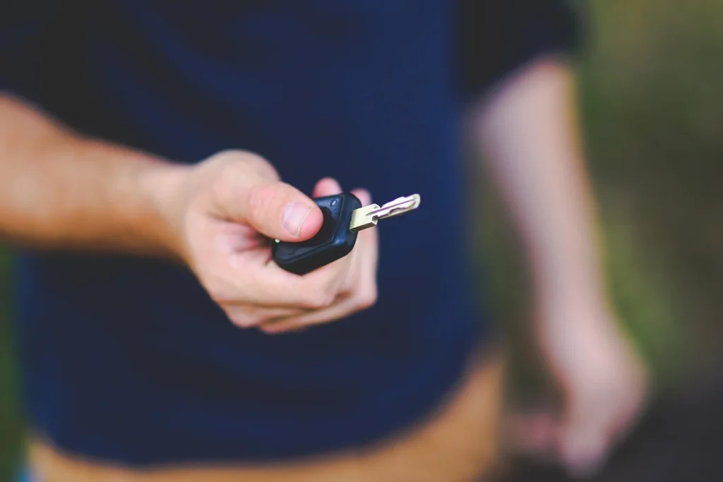 Automobilio savininkas laiko rakto pultelį šalia automobilio durų