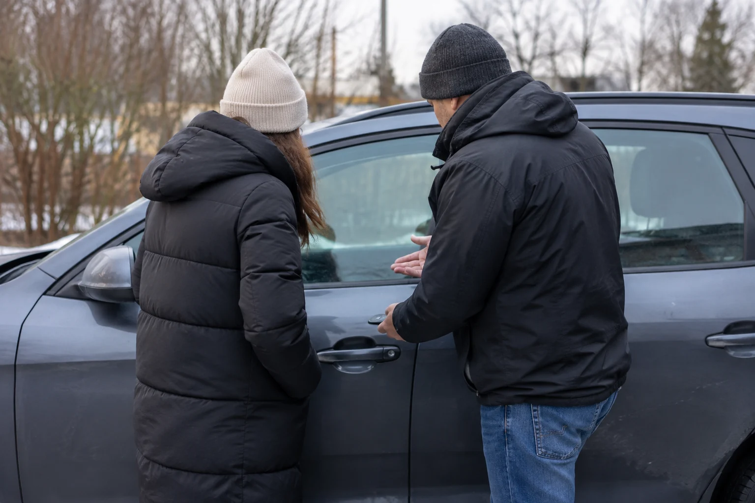 Du žmonės prie uždarytų automobilio durelių aptaria susidariusią situaciją.