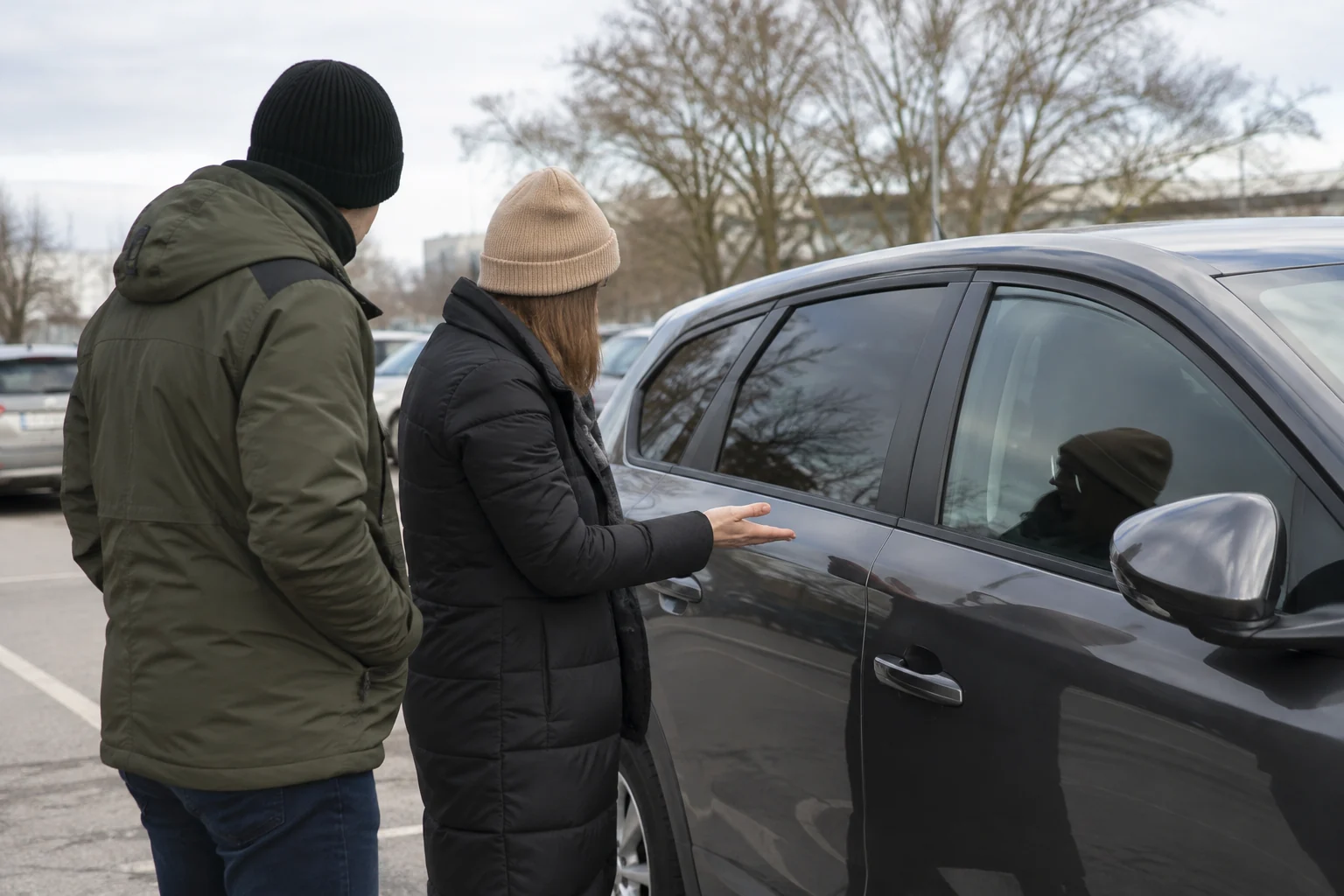 Du žmonės prie stovinčio automobilio aptaria uždarytas jo duris.